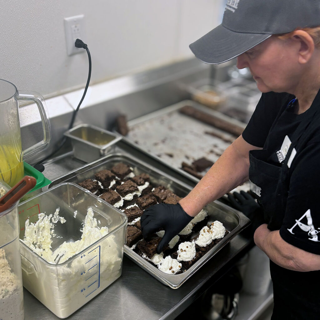 Culinary team member at Ridgemere Senior Living prepares brownies with fresh whipped cream.