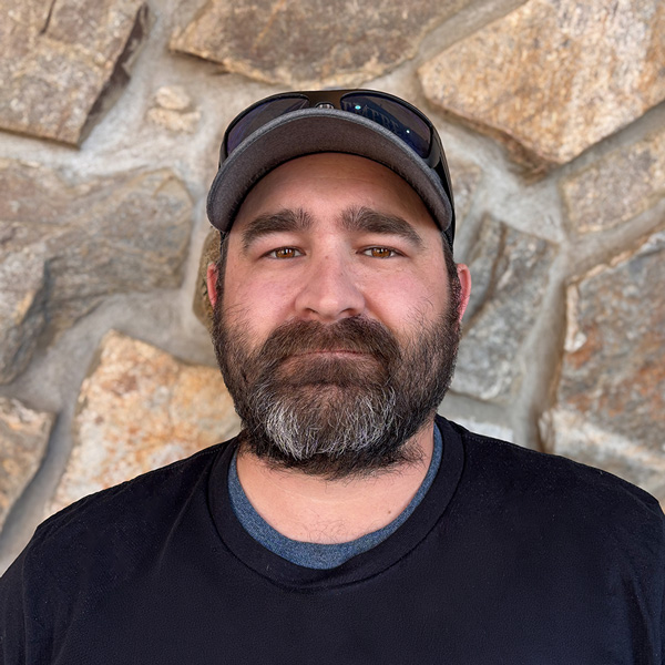Jonathan Mavity, Plant Operations Director at Ridgemere Senior Living, wearing a dark shirt and baseball cap, standing in front of a natural stone wall background.